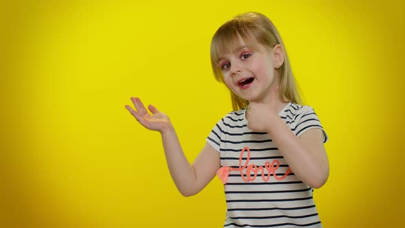 Little Kid Child Girl Showing Thumbs Up and Pointing at Left on Blank Space on Yellow Background