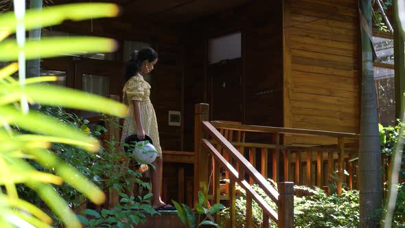 Young Woman Walking Down on the Stairs of a Veranda of a Wooden House