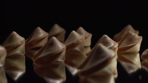 Low Key Light. A Lot of Chinese Cookies Rotate on a Black Background. Traditional Fortune Cookie