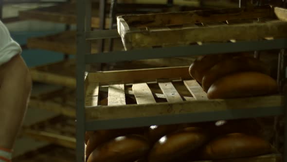 Baker Puts Freshly Baked Bread on the Shelves.