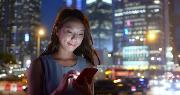 Woman use of mobile phone in the city at night