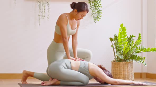 Yoga instructor training child pose with Asian women wearing green sportswear.Healthy Female doing y