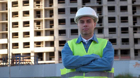 Worker with Crossed Hands in White Protective Helmet at Construction Site