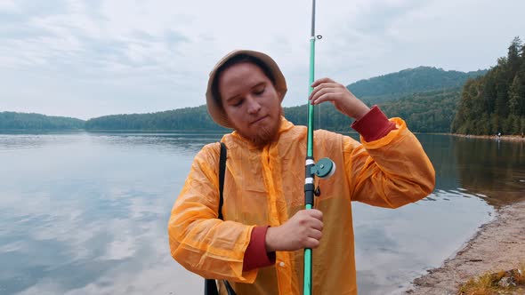 Smiling Fisherman Standing on a Shore Holding His Fishing Rod - Looking in the Camera