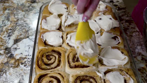 Icing homemade cinnamon rolls with cream cheese frosting