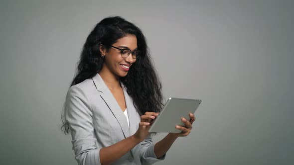 Young smiling businesswoman uses a digital table in studio shot.  Shot with RED helium camera in 8K.