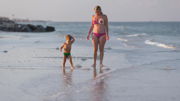 Mom Worries About Her Son and Tells Him About Poisonous Jellyfish Walking Along the Beach Strewn