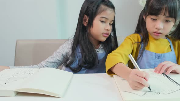 Two happy cute asian female children using laptop for remote education