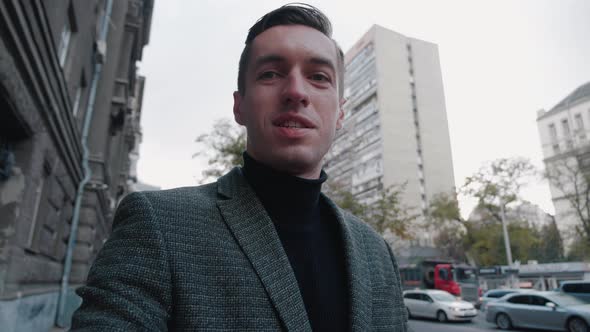 Smiling Young Business Man Making Selfie Video Call While Walking Outdoor at City Street. Portrait