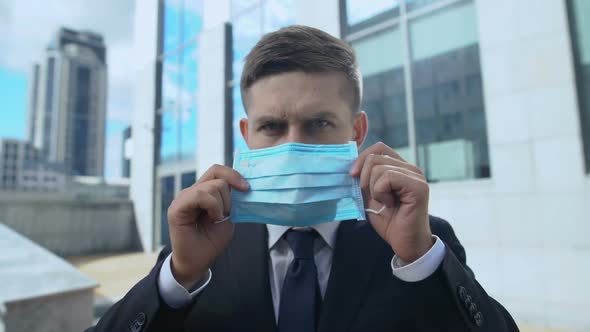 Serious Man in Suit Putting on Protective Mask, Seasonal Flu Epidemic in Country