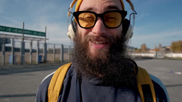 Portrait of a Stylish Bearded Man in Yellow Clothes Enjoying Music with Headphones on the Blue Sky