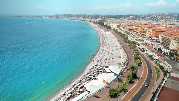 View of the cote d'Azur in Nice, France. Multiple resting on the beach people, buildings, blue water