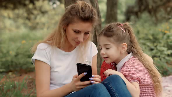 Little Small Child With Mother Make Video Call In Internet Social Network. Girl Sitting With Mother