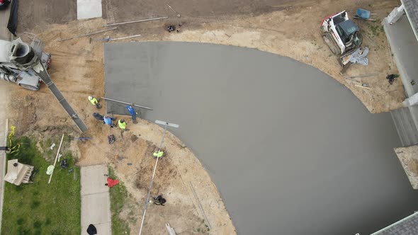 Top down view of cement workers finishing up a new driveway with floats and shovels.