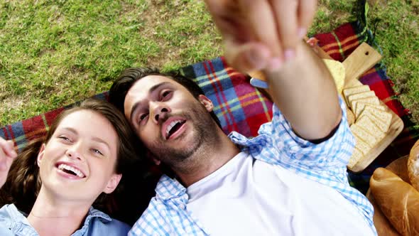 Couple interacting with each other while lying on picnic blanket