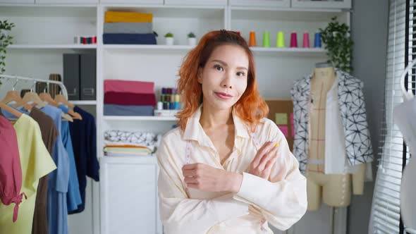 Portrait of Asian tailor woman working on clothes in tailoring atelier.