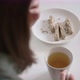 Young woman brunette tastes delicious halva slice holding white cup with tea. Breakfast - VideoHive Item for Sale