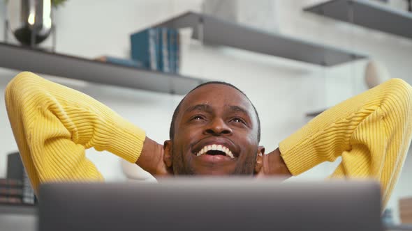 Happy man relaxing at work with laptop at home office. Young businessman with laptop indoors