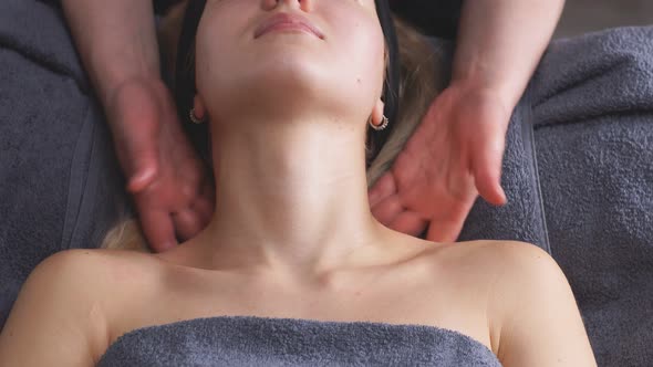 An Attractive Woman Lies on a Bed in a Beauty Salon and Gets a Massage on the Decollete and Neck