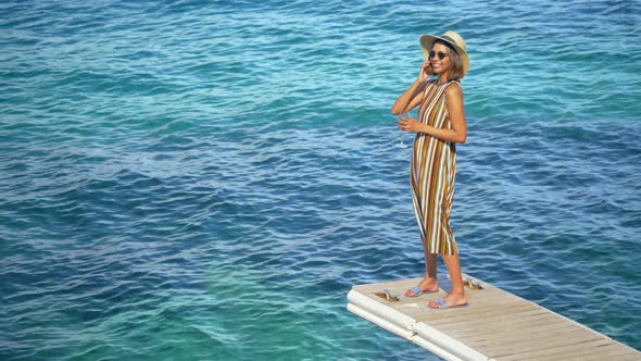 A woman with a glass of white wine on a dock over the Mediterranean Sea in Italy, Europe