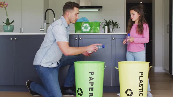 Happy caucasian father and daughter segregating rubbish in kitchen