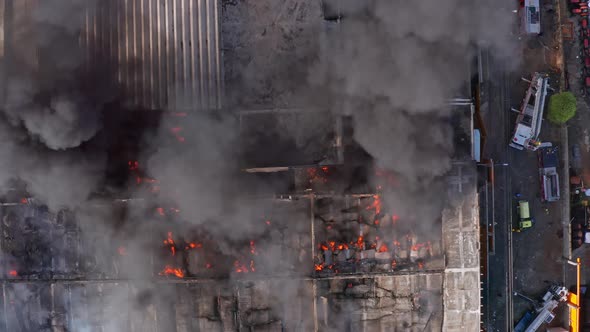 Aerial view above a industrial fire, firetrucks on side - top down, drone shot