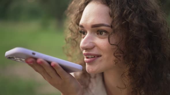 Headshot Young Brunette Curlyhaired Caucasian Woman Smiling Talking at Smartphone Speakerphone