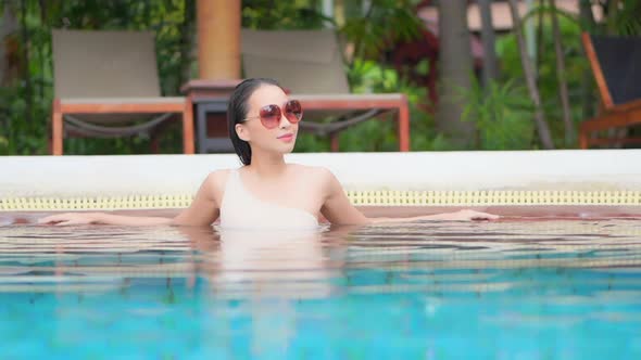 Young asian woman enjoy around outdoor swimming pool for leisure