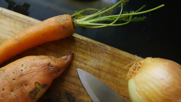 Onion, carrot and sweet potato with knife at home