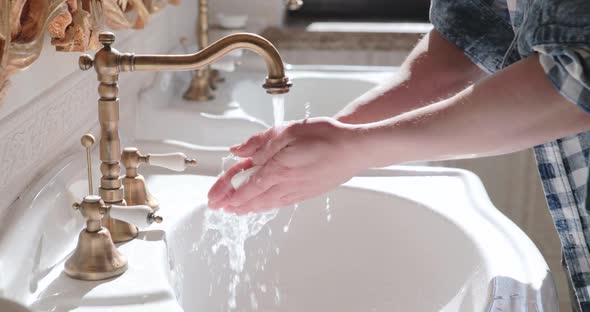 Man Turns on Flowing Faucet Soaps Hands Washes Them Under Water in Toilet Room