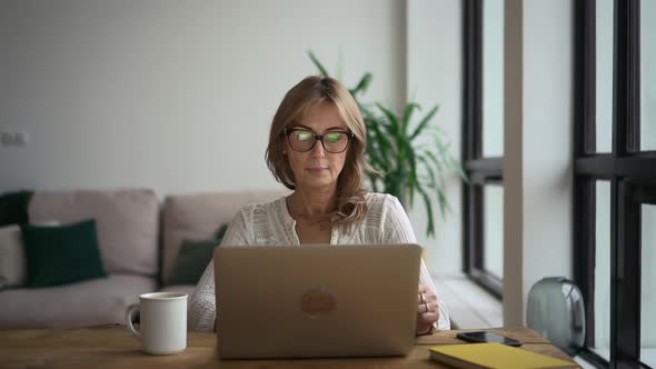 Businesswoman Working with Laptop and Having Break at Table in Home Office