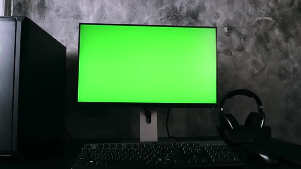 Black computer with green screen monitor on the desk in the dark room at home