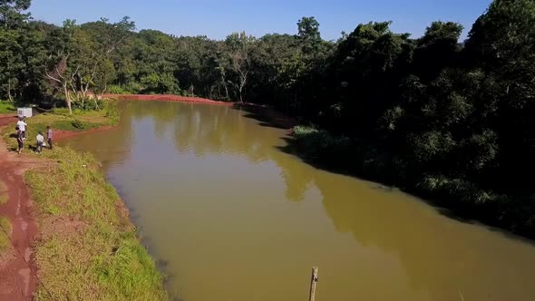 Wide drone view flying slowly over a small pond on a commercial fish farm in Tocantins region of Bra
