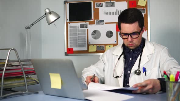 A Young Doctor Signs Documents at the End of the Day in the Private Clinic