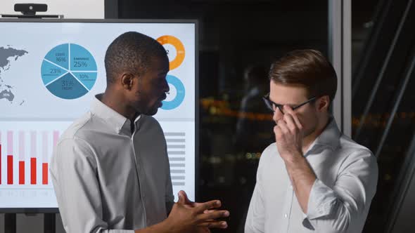 Two colleagues of different ethnicity discussing a presentation