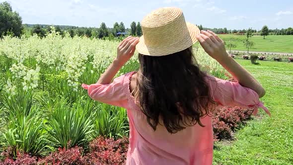 Attractive Girl in Elegant Pink Clothes Standing Happily Near the Field of Flowers in Summer