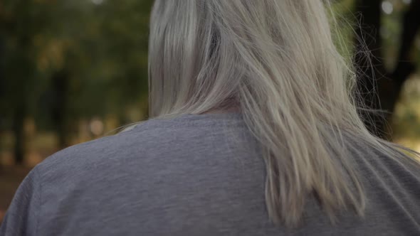 Woman walking through park in Autumn over the shoulder medium shot