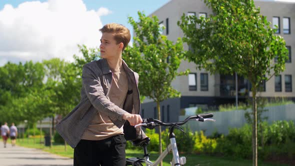 Young Man with Bicycle Walking Along City Street