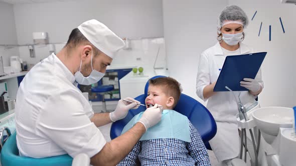 Male Doctor and Nurse Assistant Examining Mouth Cavity of Kid