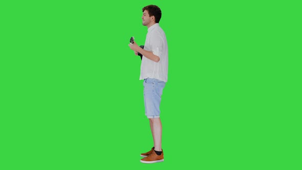 Smiling Young Man Playing Ukulele Looking Into the Camera on a Green Screen, Chroma Key.