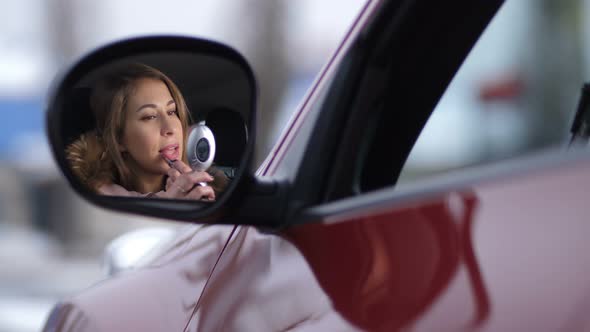 Beautiful Girl in the Car Paints Lips with Pink Lipstick