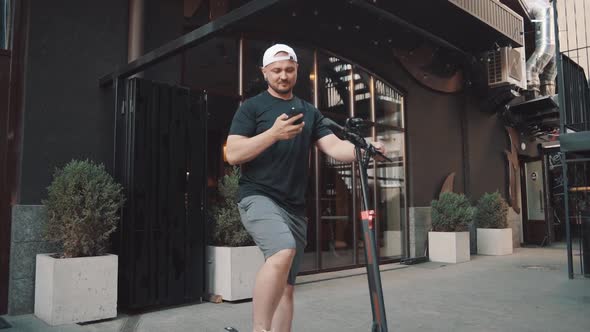 Tourist Man on Electric Scooter with Phone in Hand