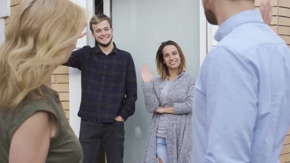 Pleasant Caucasian Family Standing at Doors, Waving and Smiling