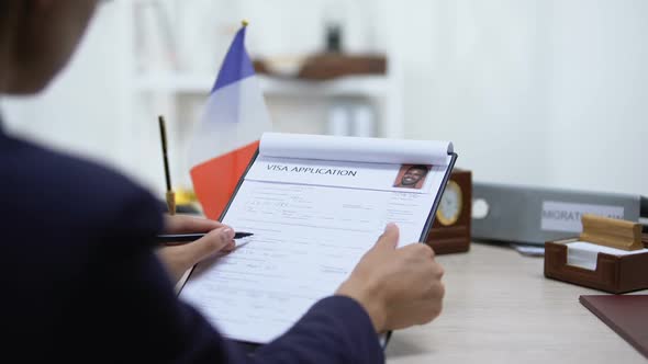 Embassy Employee Approving Visa Application, French Flag on Table, Migration Law
