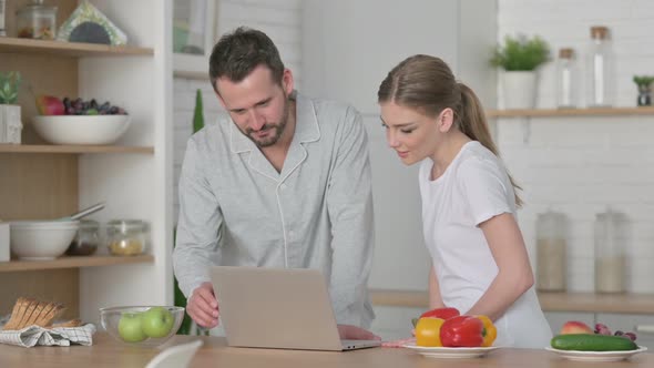 Woman and Man Working on Laptop in Kitchen