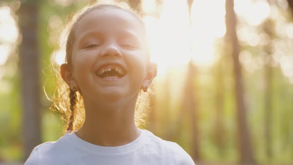 Portrait of Pretty Little Girl Looking at Camera Smiling and Laughing Outdoors