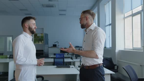 Two Bearded Men in White Shirts Talk in an Office