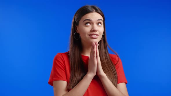 Beautiful Woman in Orange Tshirt Praying Over Blue Background