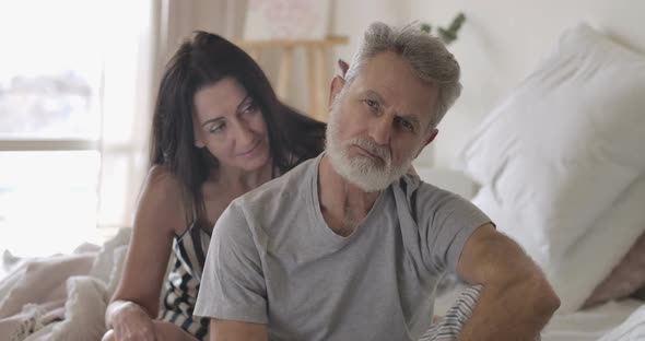 Portrait of Upset Senior Caucasian Man Looking at Camera and Moving Away Wife's Hand. Offended