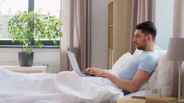 Man with Laptop in Bed at Home Bedroom